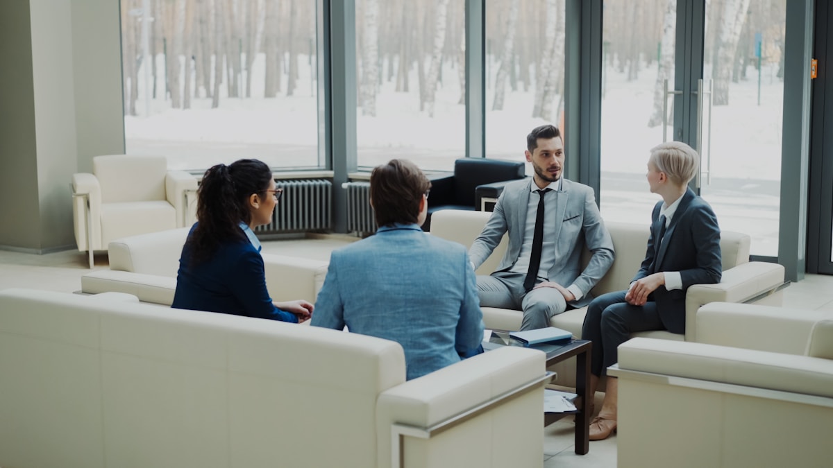 Four professionals in a modern office meeting space.