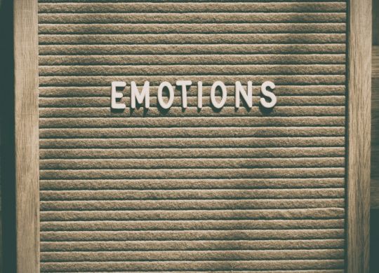 Wood-framed letter board with the word “EMOTIONS” in white letters on a textured beige background.