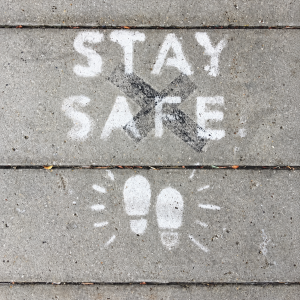 Mensagem Stay Safe pintada no pavimento, com pegadas, para ilustrar segurança e saúde no trabalho