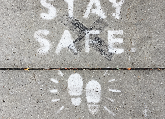 Mensagem Stay Safe pintada no pavimento, com pegadas, para ilustrar segurança e saúde no trabalho