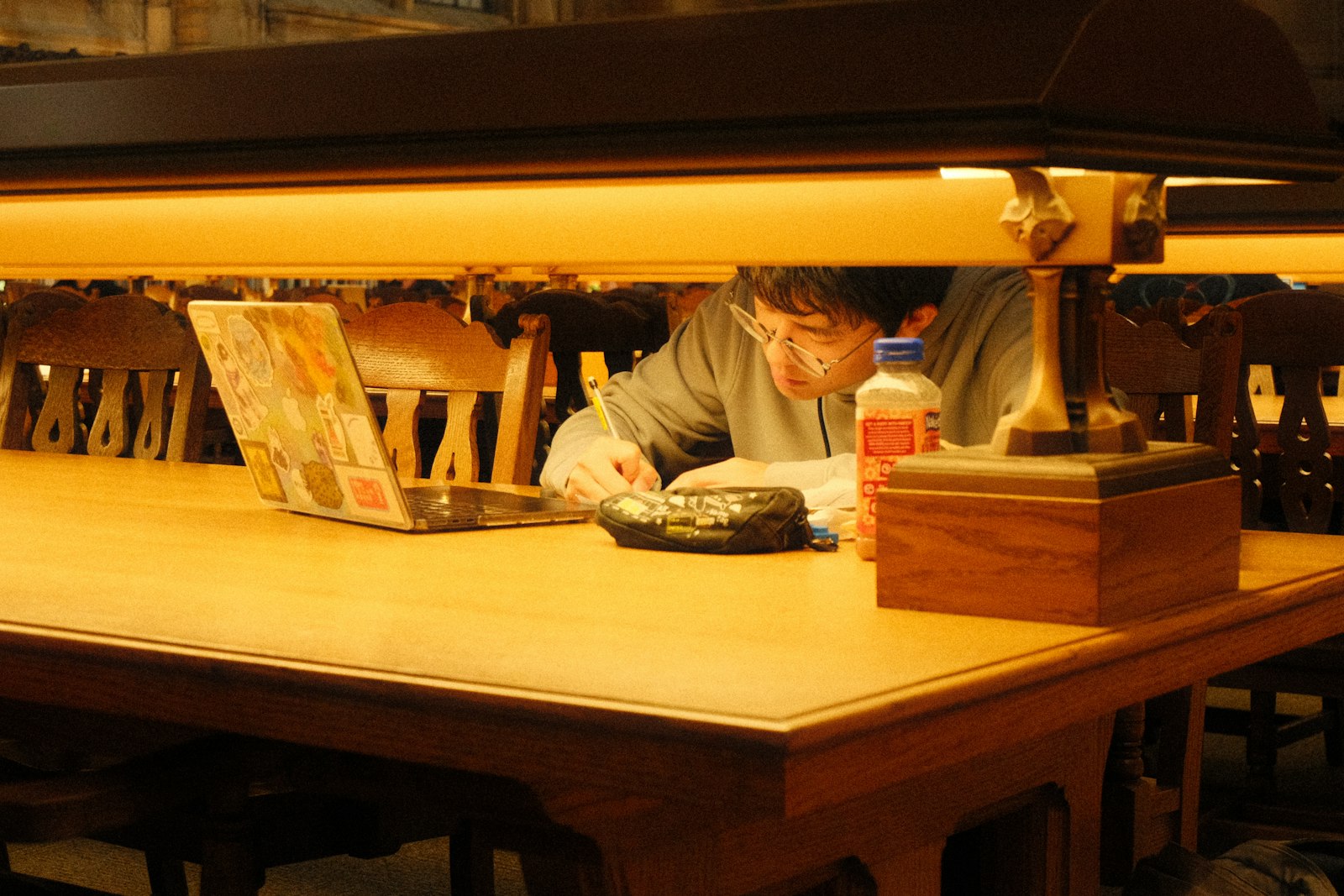 Pessoa a estudar com um portátil e a tomar apontamentos numa biblioteca.